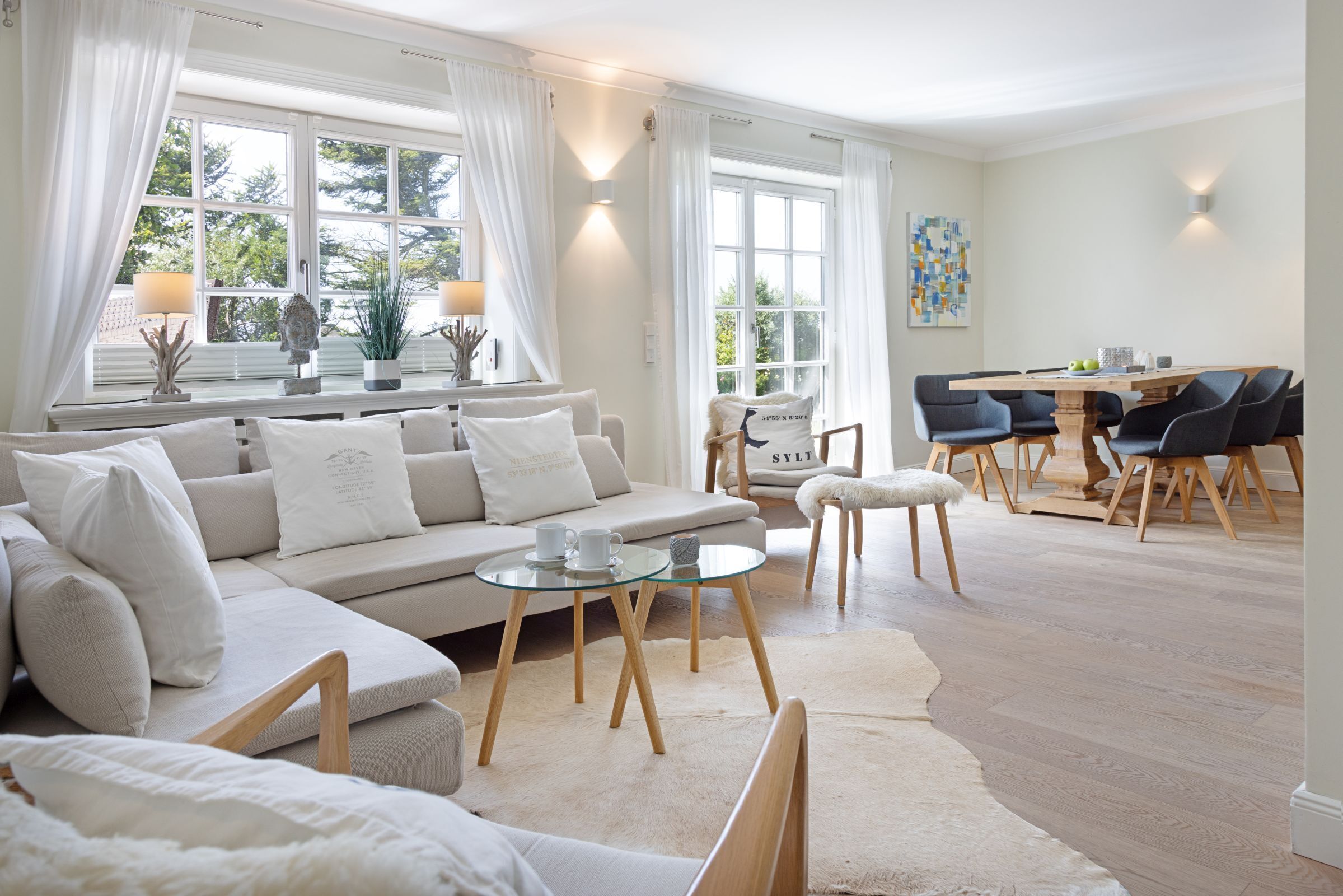 A spacious living room with a large sofa, a glass coffee table, and a dining area with a wooden table and chairs.