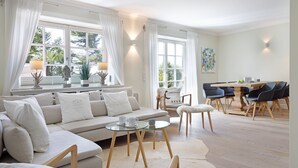 Ein geräumiges Wohnzimmer mit einer großen Couch, einem Glastisch und einem Essbereich mit einem Holztisch und Stühlen.
