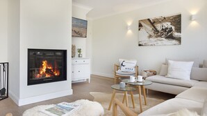 Ein Wohnzimmer mit Kamin, einer Couch, einem Couchtisch und einem Teppich.