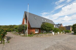 A house with a sloped roof, a stone wall, and a gravel driveway.