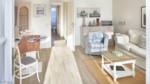 Un grand espace de vie comprenant une table à manger, un canapé et une table basse. On y trouve également un meuble contenant des objets décoratifs et un téléviseur.