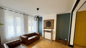 Una sala de estar con un sofá de cuero, una chimenea y un candelabro colgante.