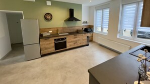 Una cocina moderna con horno empotrado, lavavajillas y un amplio ventanal con persianas.