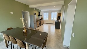 Una cocina moderna con comedor, que incluye una mesa grande, sillas y un refrigerador.
