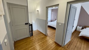 Un pasillo con piso de madera que conduce a un dormitorio con una cama y una mesita de noche.