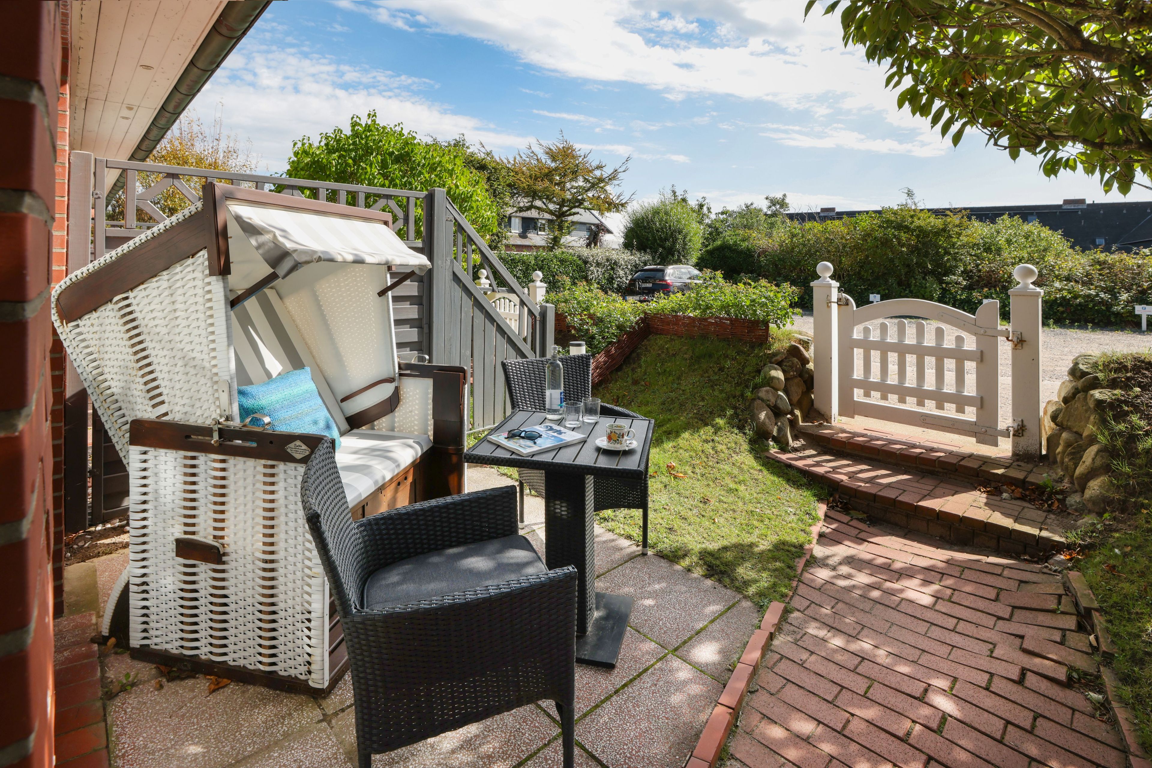 A patio with wicker furniture, a table with a magazine, and a view of the street.