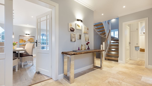 Un intérieur moderne comprenant un escalier, un coin repas et un couloir agrémenté d’œuvres d’art.