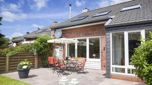 En terrasse med et bord, stole, en potteplante og et træhegn.