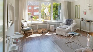 En lys stue med stort vindue, hvid sofa, sofabord og lille sofabord.