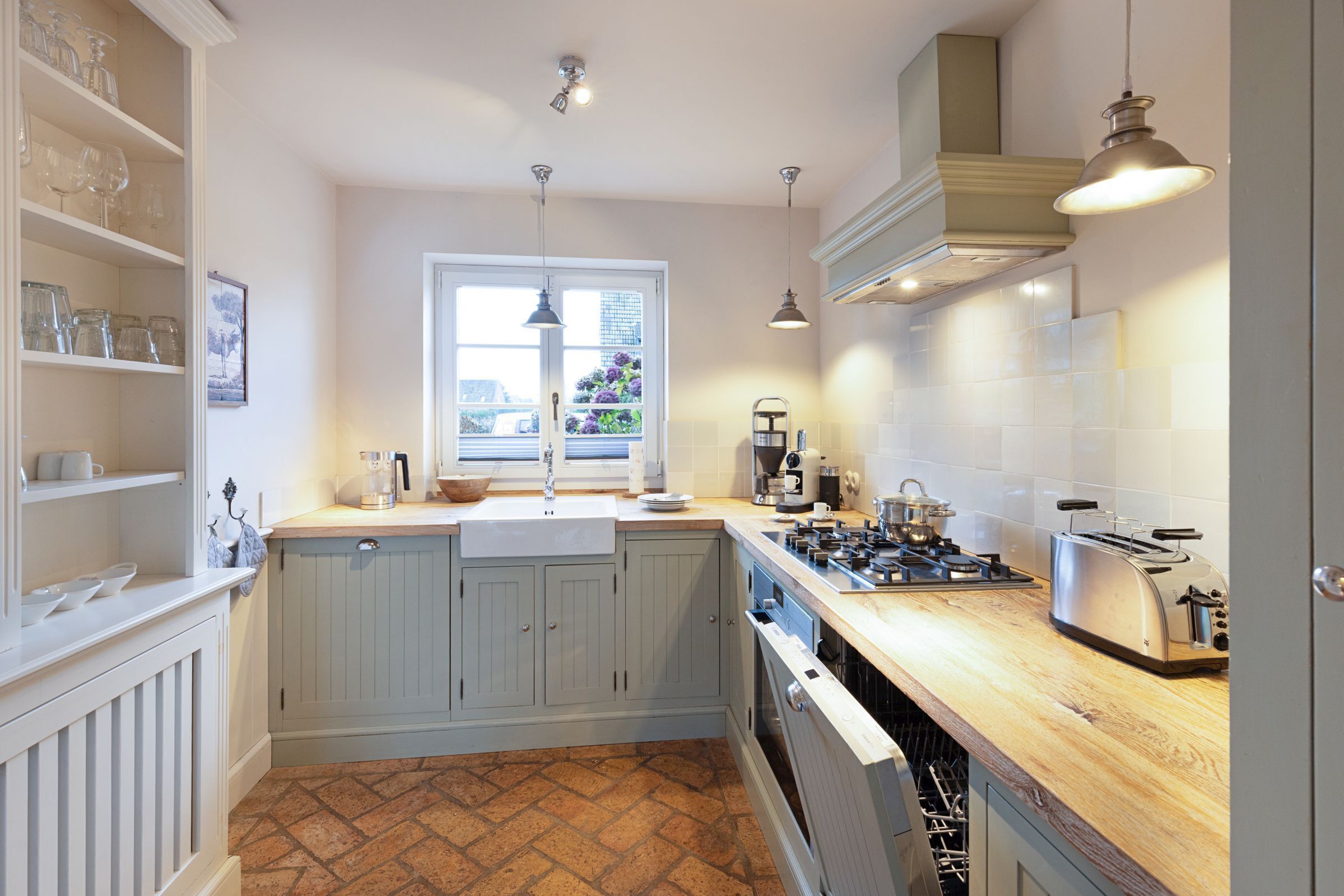 A kitchen with white cabinets, a wooden countertop, a window with a view of greenery, and a gas stove.