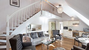 A spacious living area with a staircase, a dining table with chairs, and a kitchen in the background. - Herzlich Willkommen im Appartement Southend (List)