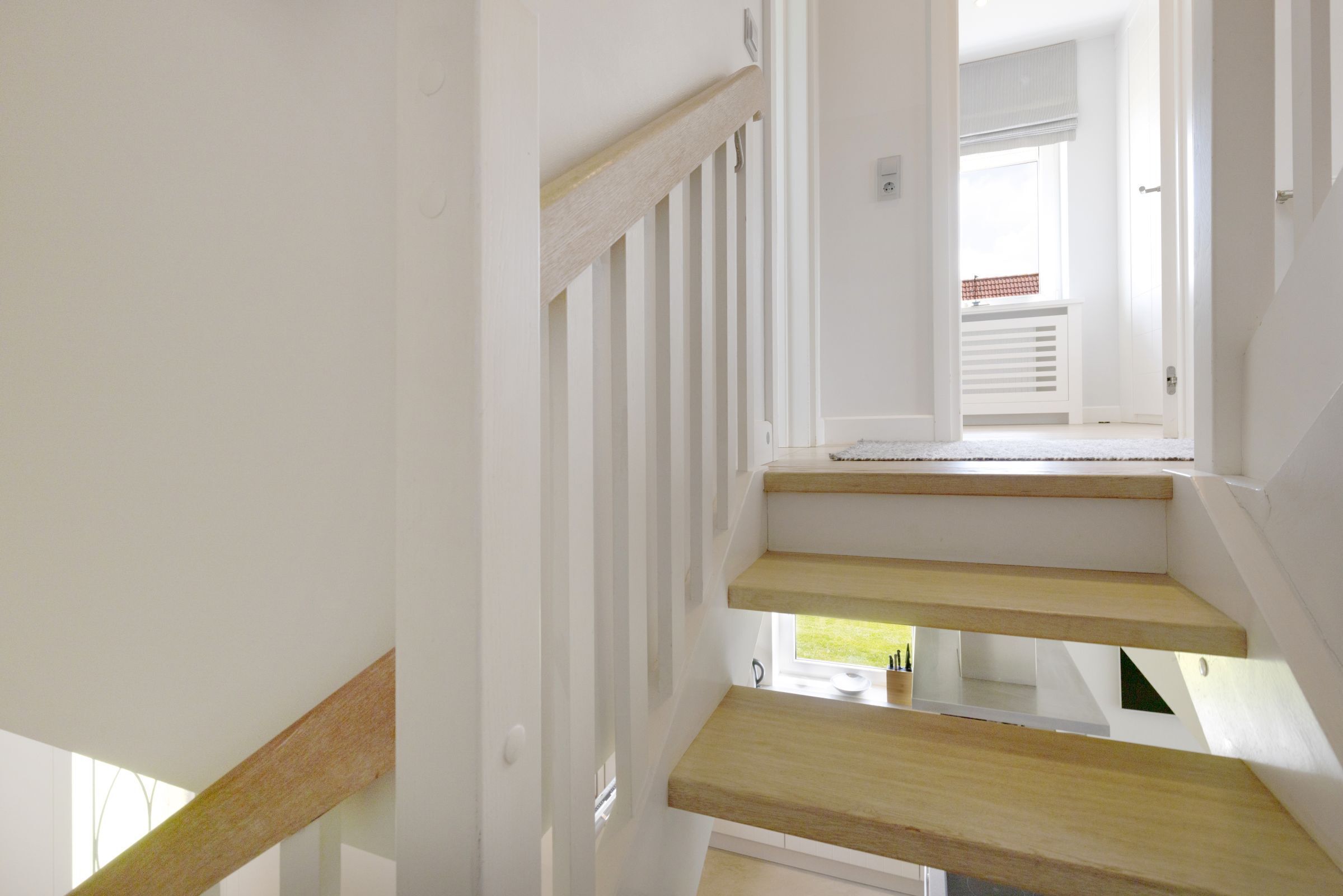Un escalier avec des marches en bois et des rampes blanches menant à un palier.