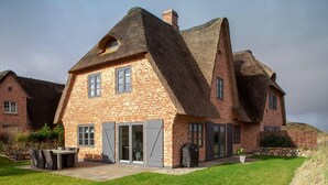 A large brick house with a steeply pitched roof and a chimney. - Herzlich Willkommen im Ferienhaus Ellenbogenblick (List)