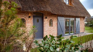 A traditional brick house with a thatched roof, a grey door, and a window with shutters. - Herzlich Willkommen im Ferienhaus Ellenbogenblick (List)