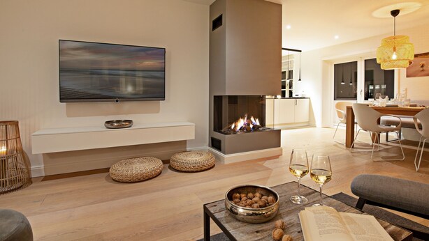 A modern living room with a fireplace, a flat-screen TV, and a dining area. - Herzlich Willkommen im Ferienhaus Ellenbogenblick (List)