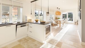 A modern kitchen with white cabinetry, a central island, and pendant lighting. - Herzlich Willkommen im Ferienhaus Ellenbogenblick (List)
