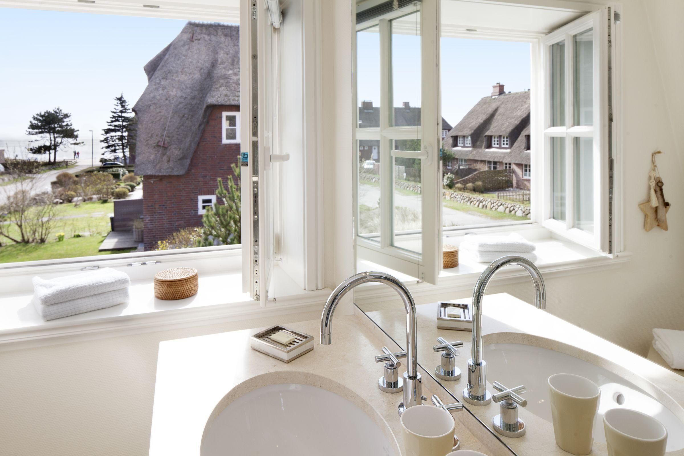 A bathroom with a large window, a sink, and a mirror.
