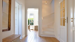 A hallway with a wooden bench, white doors, and a staircase leading to an outdoor area with a view of greenery. - Welcome to the vacation home "Ferryview". (List)