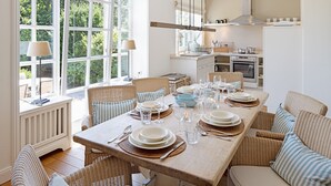 A dining area with a large table set for six, surrounded by wicker chairs. - Welcome to the vacation home "Ferryview". (List)