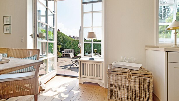 A bright room with a large window, wicker furniture, and a radiator. - Welcome to the vacation home "Ferryview". (List)