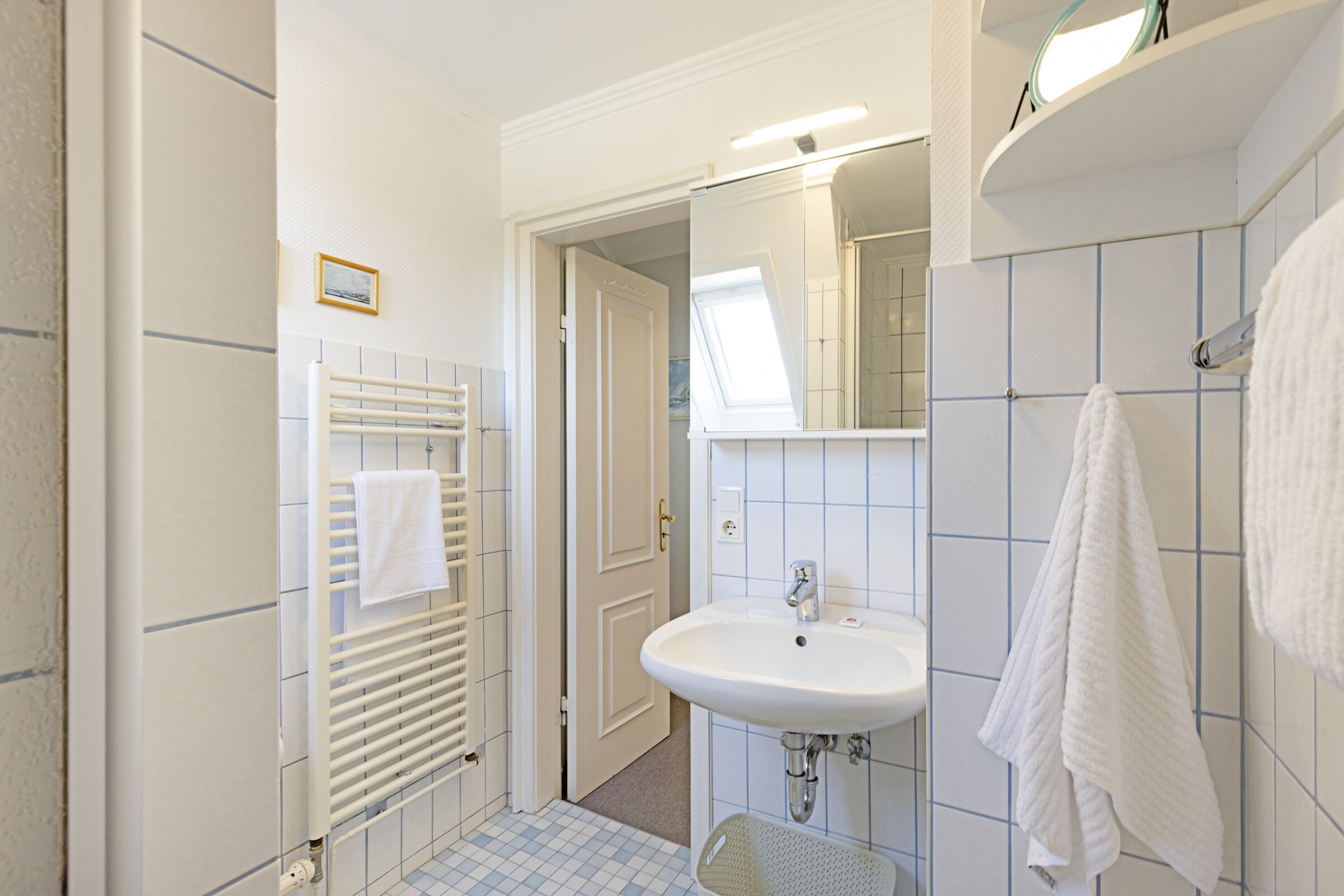 A bathroom with a white sink, a towel rack, and a mirror.