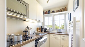 Una cocina moderna con muebles blancos, electrodomésticos de acero inoxidable y un ventanal que proporciona luz natural.
