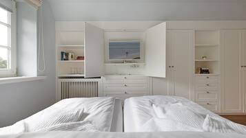 A bedroom with a bed, a TV, and a white wardrobe.
