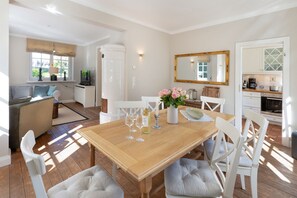 A dining area with a wooden table, white chairs, and a vase of flowers.