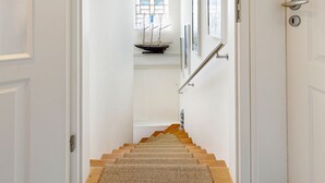 Una escalera con escalones de madera y una alfombra tejida al pie.