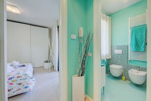 A bedroom with a bed, a bathroom with a sink and toilet, and a shower area. - Green Tiffany Apartment (Desenzano del Garda)