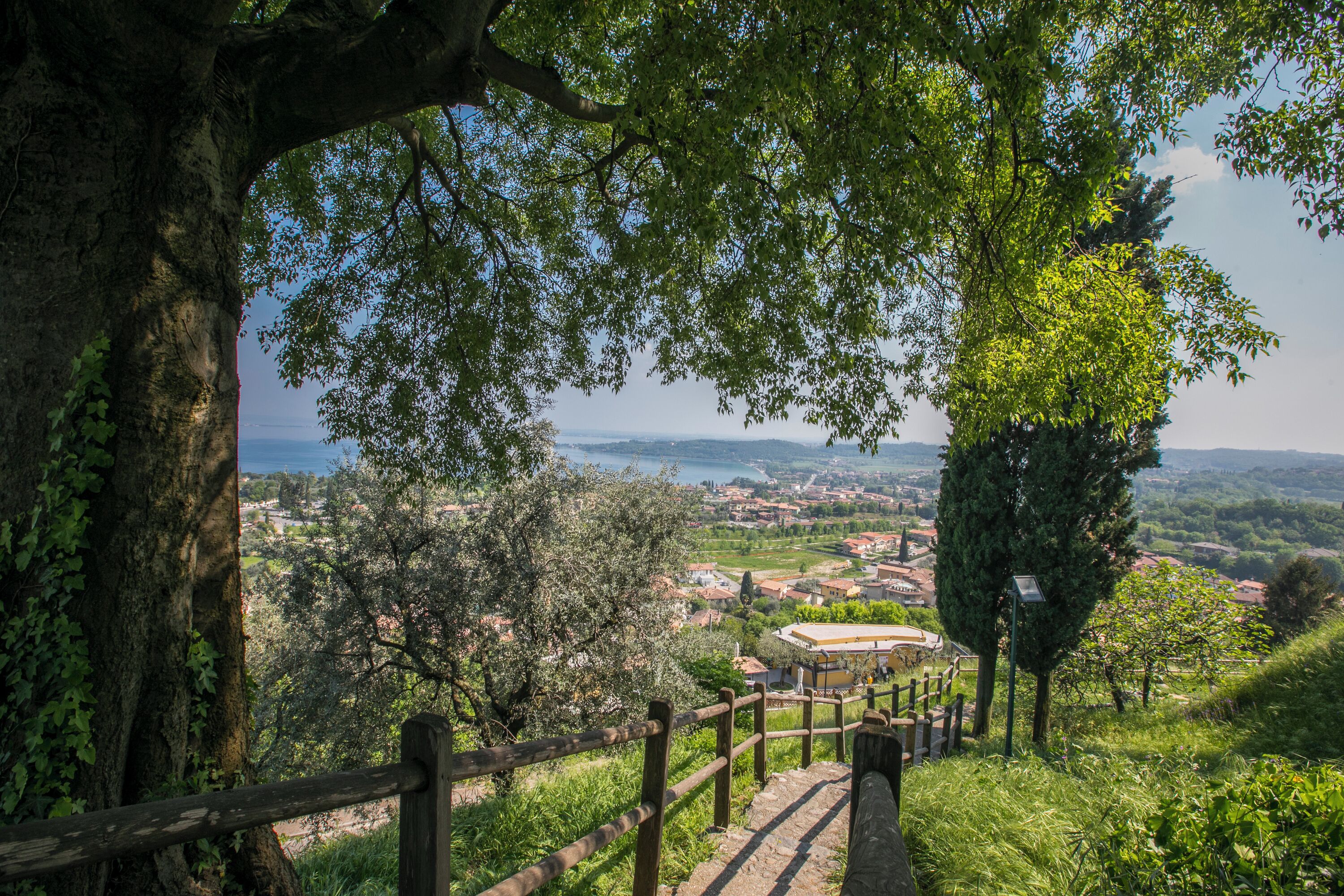 A scenic view from a hilltop with a wooden staircase leading down, overlooking a town and a body of water.