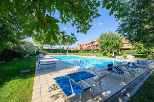 Una piscina con sillas de descanso y un borde empedrado.