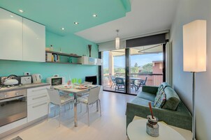 Una cocina moderna con comedor, un sofá y un balcón con mobiliario exterior.