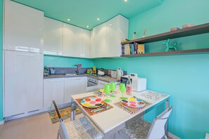 Una cucina moderna con mobili bianchi, un tavolo da pranzo con sottopiatti colorati e una parete verde acqua.