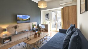 A modern living room with a sofa, a coffee table, a TV, and a bookshelf. - Marnis10 3rd (Athens)
