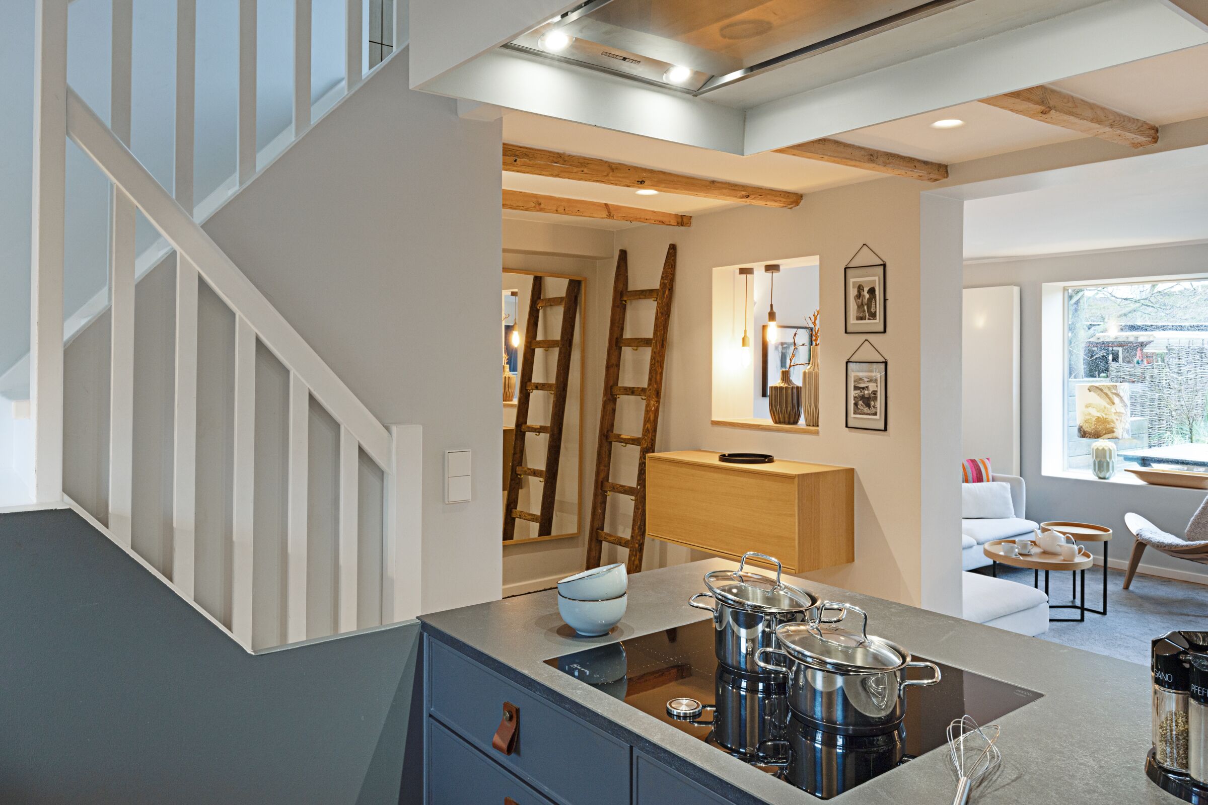 A modern kitchen with a central island, built-in appliances, and a staircase leading to an upper level.