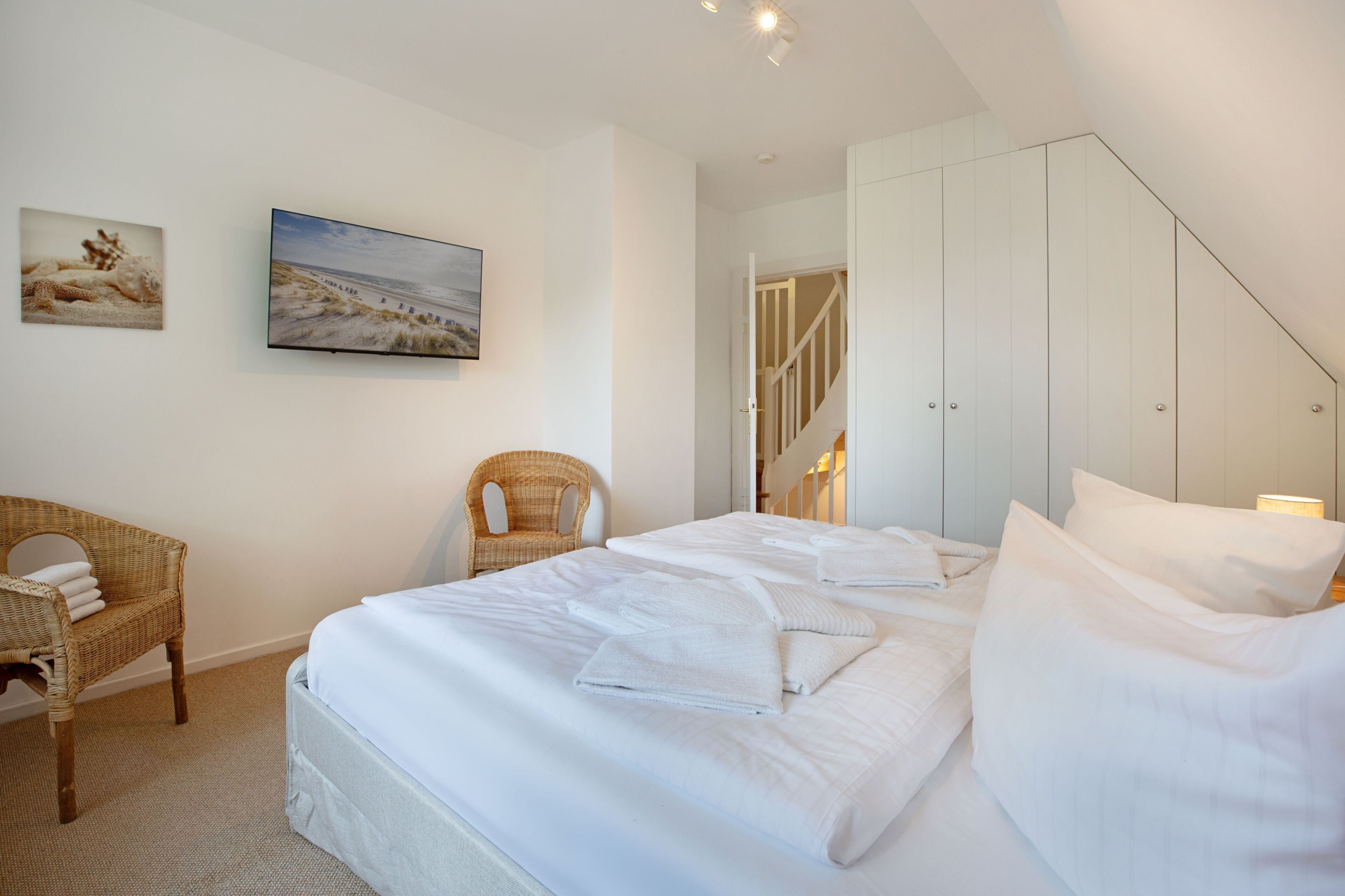 Une chambre d’hôtel avec un lit, une chaise et deux tableaux accrochés au mur.