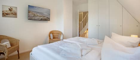 Una habitación de hotel con una cama, una silla y dos cuadros en la pared.