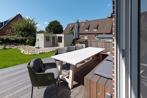 Relax on the patio surrounded by a beautifully maintained lawn and brick walls, with a comfortable table and chairs.