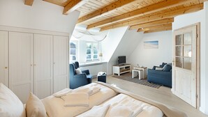 Un dormitorio con una cama grande, un escritorio, una silla y un sofá.