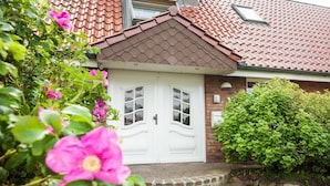Ein Haus mit rotem Ziegeldach, weißen Doppeltüren und einer Ziegelaußenwand.