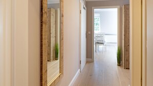 A hallway with a wooden-framed mirror, a door, and a view of a balcony with outdoor furniture.