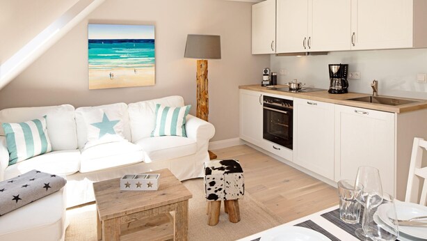 A modern kitchen with white cabinets, a wooden countertop, and a coffee maker.