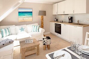 A modern kitchen with white cabinets, a wooden countertop, and a coffee maker. - Herzlich Willkommen im Appartement Sylter Perle (List)
