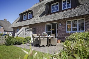 Traditional home with a spacious patio and wicker furniture, perfect for relaxing.
