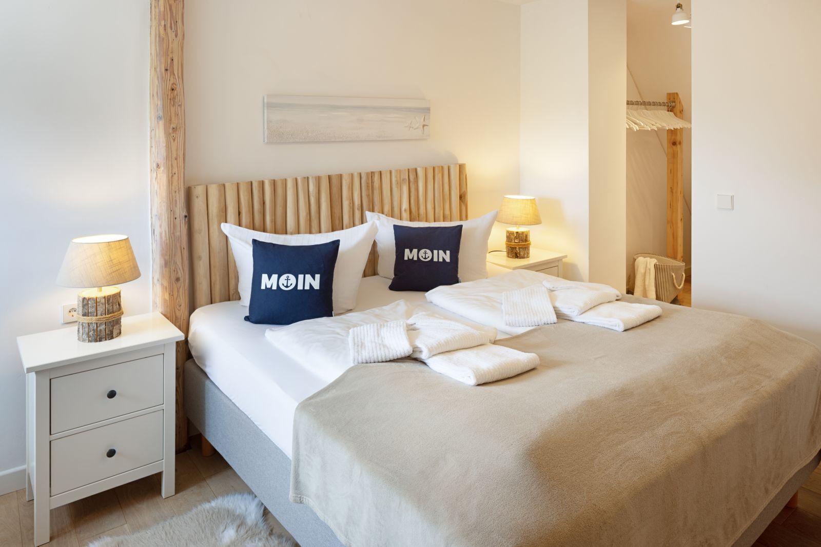 A neatly made bed with two pillows, a bedside lamp, and a small bedside table with a lamp.