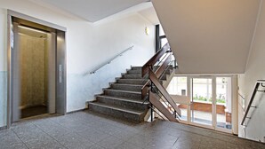 Ein modernes Interieur mit Treppe, Aufzug und großen Fenstern.