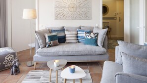 Ein modernes Wohnzimmer mit einer grauen Couch, gemusterten Kissen, einem kleinen Couchtisch und einer Wanddekoration.