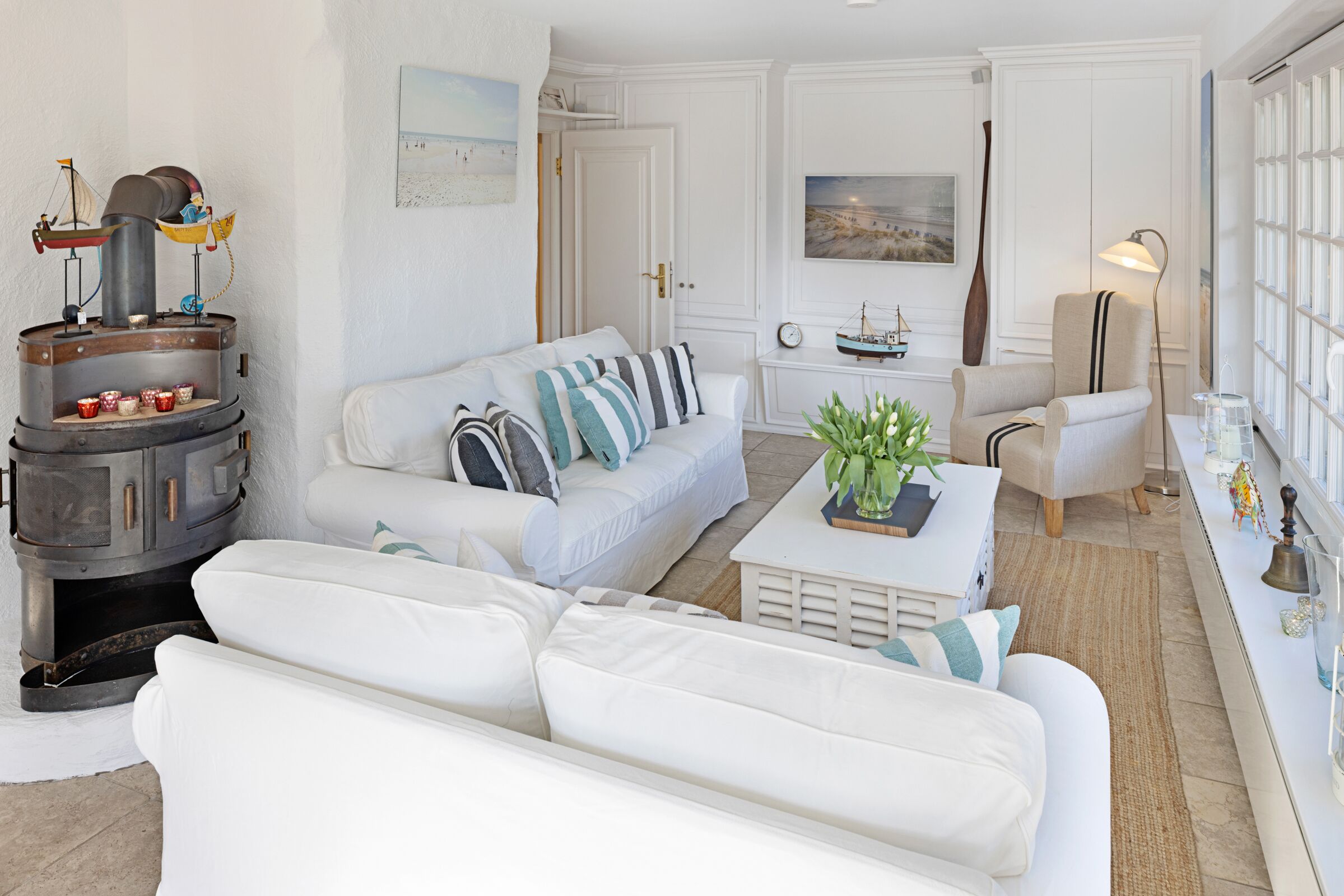 Un salón moderno con un sofá blanco, una mesita de centro con una planta y una estufa decorativa.