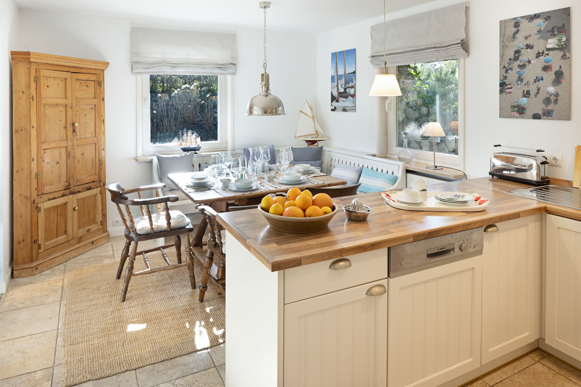 A kitchen with a wooden island, white cabinetry, and a view of the outdoors through a window.